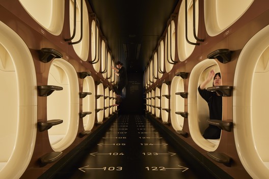 Row of white sleeping capsules along a lit interior corridor